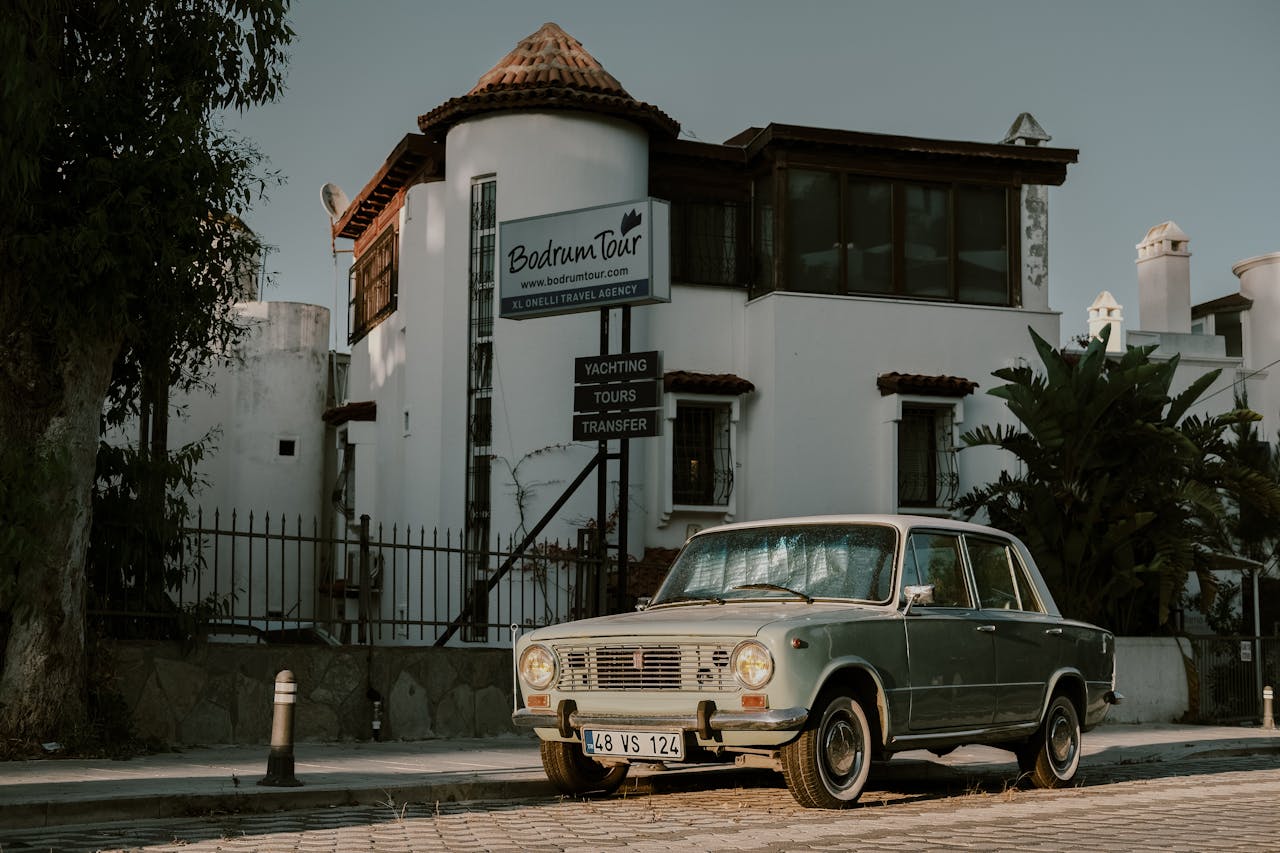 Classic vintage car parked outside Bodrum Tour Agency in Bodrum, Turkey, during daylight.